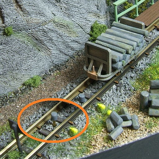 The lowered stopper rests below the upper edge of the track; when raised, it is at the height of the axles.
